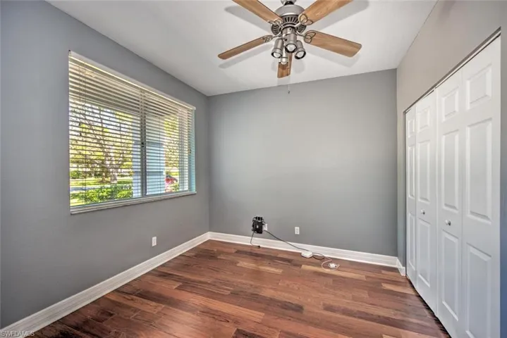 Bedroom with a closet, dark wood finished floors, and baseboards