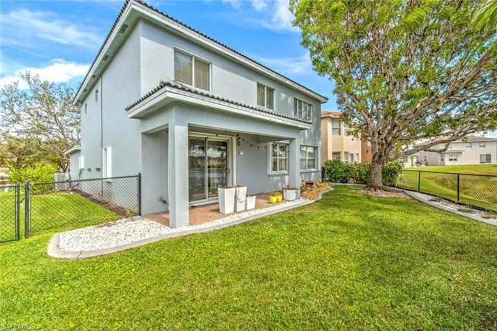 Rear view of property featuring a yard, fence, a gate, and stucco siding