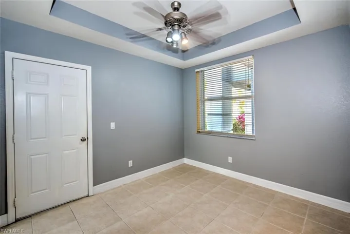 Unfurnished room featuring baseboards, a raised ceiling, and a ceiling fan