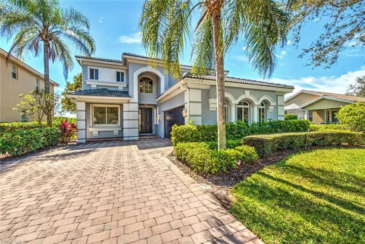 Mediterranean / spanish-style home featuring a garage, a tiled roof, decorative driveway, stucco siding, and a front yard