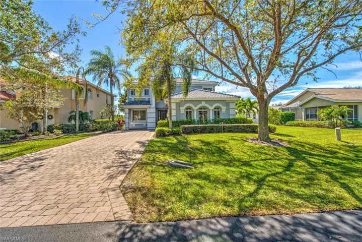 Mediterranean / spanish-style house featuring a tiled roof, a front lawn, and decorative driveway