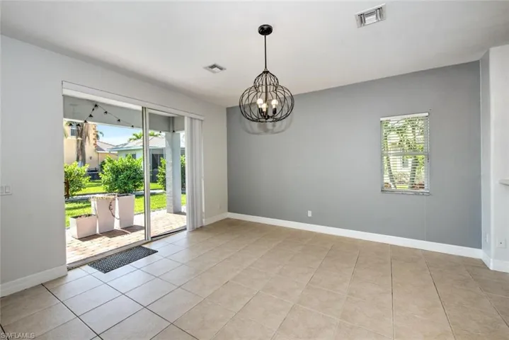 Unfurnished room featuring light tile patterned floors, baseboards, visible vents, and a chandelier