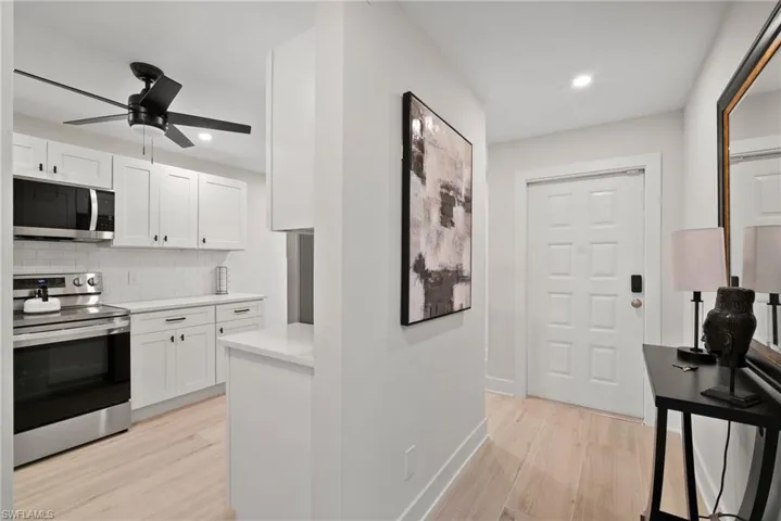 Kitchen with white cabinetry, decorative backsplash, appliances with stainless steel finishes, and light hardwood / wood-style flooring