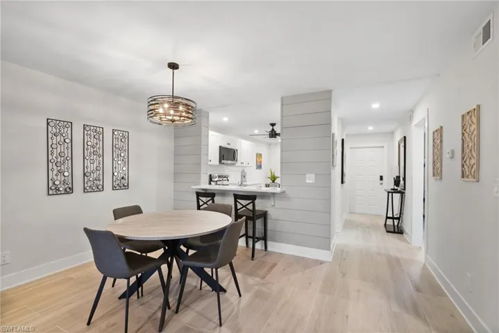 Dining space with ceiling fan with notable chandelier, sink, and light wood-type flooring
