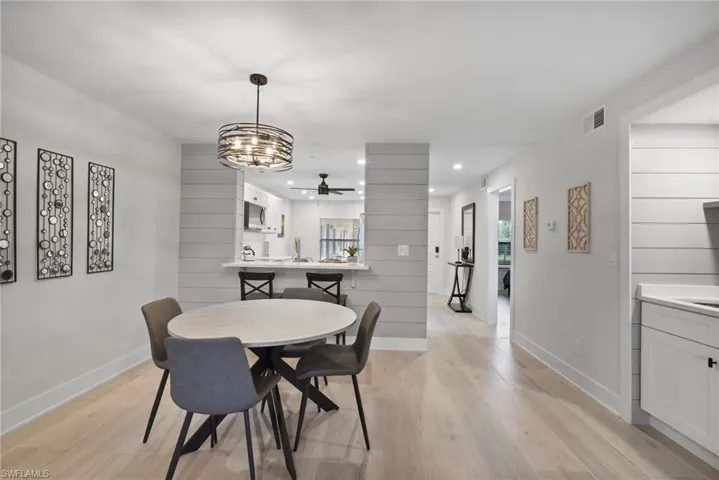 Dining area with ceiling fan with notable chandelier and light hardwood / wood-style floors