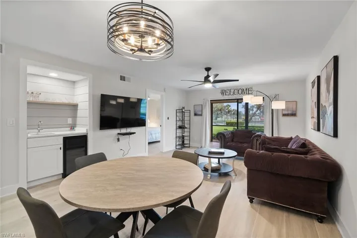 Dining space with light hardwood / wood-style floors, ceiling fan with notable chandelier, sink, and wine cooler