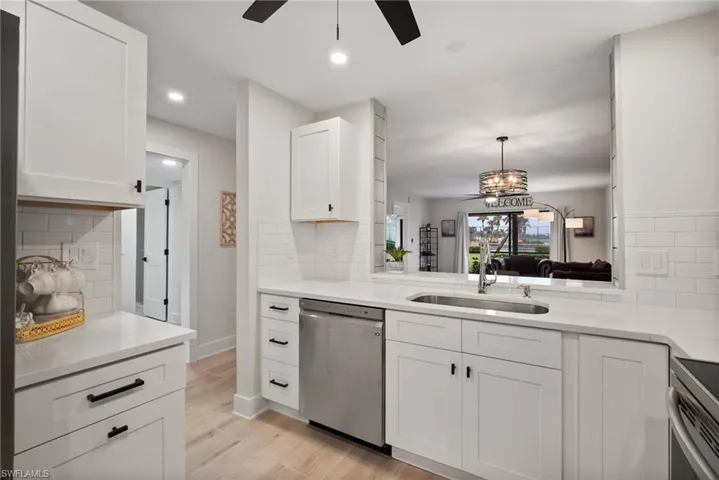 Kitchen featuring stainless steel appliances, light hardwood / wood-style floors, sink, backsplash, and white cabinets