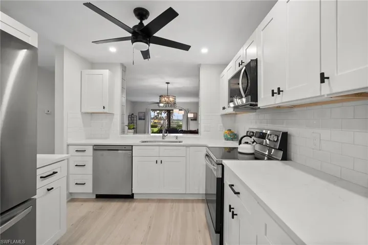 Kitchen featuring stainless steel appliances, pendant lighting, sink, light hardwood / wood-style floors, and white cabinets