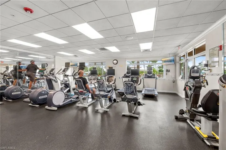 Fitness center featuring large windows, full-length mirrors, recessed lighting, and rubber flooring
