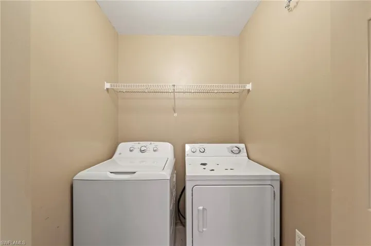 Dedicated laundry area featuring a white top-load washing machine, a white front-load dryer, and a white wire shelf