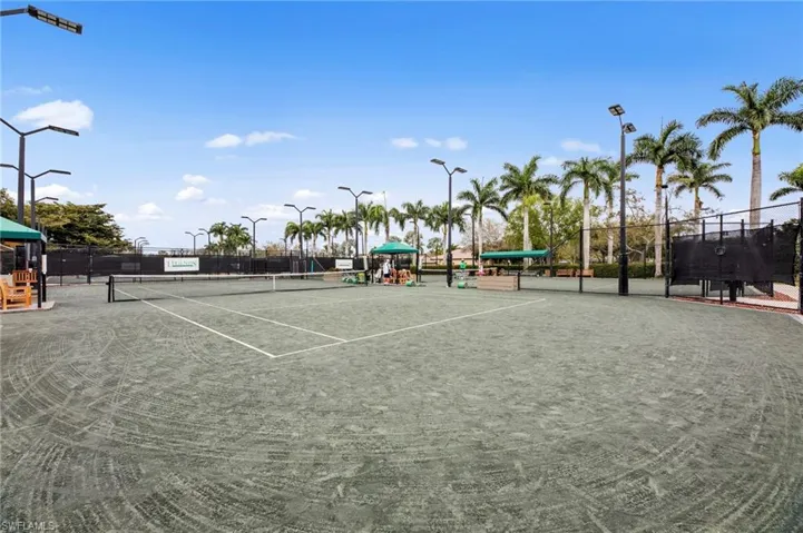 Regulation-size tennis courts with perimeter fencing and dedicated lighting structures