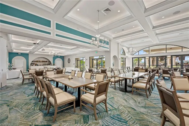 Spacious interior featuring decorative coffered ceilings with recessed lighting, a built-in bar area with arched alcove, floor-to-ceiling glass doors, and large arched windows