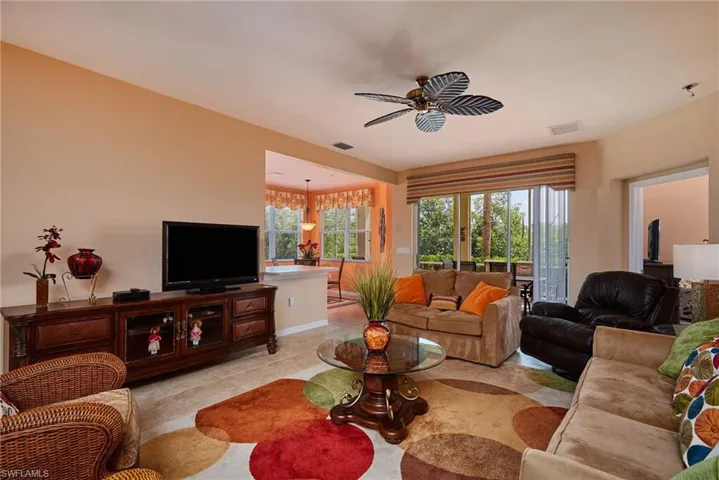 Living room with a ceiling fan and light tile patterned flooring