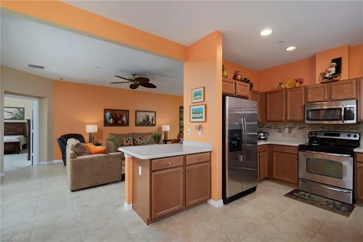 Kitchen with appliances with stainless steel finishes, light countertops, tasteful backsplash, open floor plan, and brown cabinetry