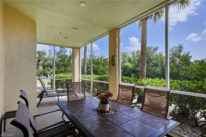 Sunroom / solarium with a textured wall, a wall of windows, outdoor dining area, and a textured ceiling