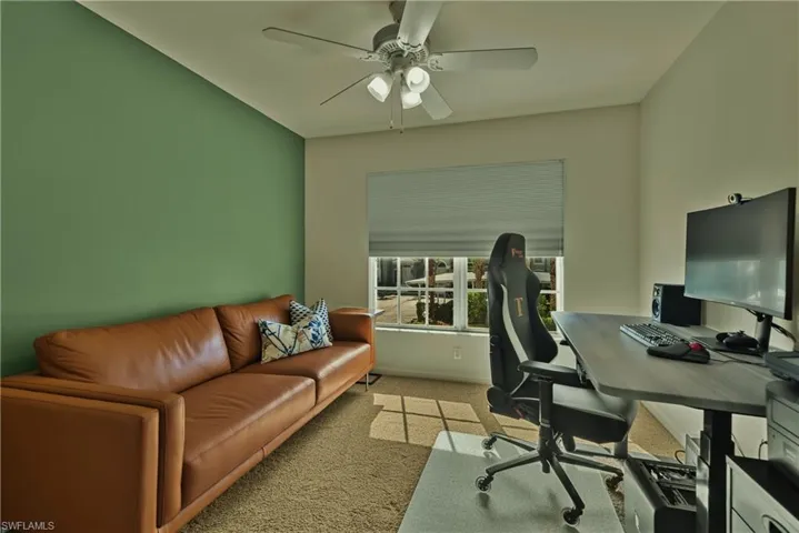 Carpeted office featuring ceiling fan