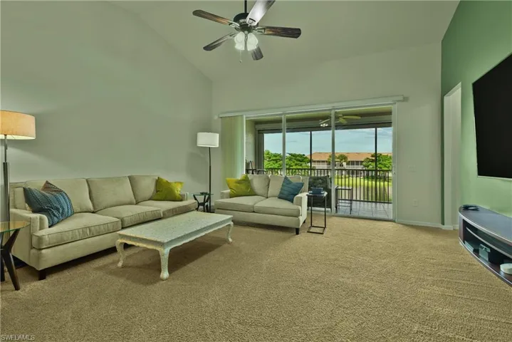 Living room with light colored carpet, high vaulted ceiling, and ceiling fan