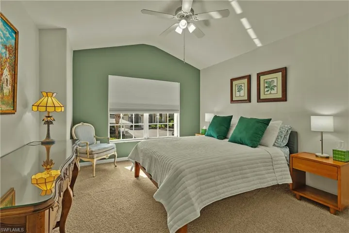 Carpeted bedroom featuring ceiling fan and lofted ceiling