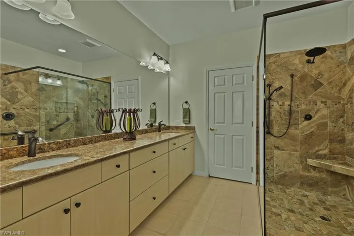 Bathroom featuring tiled shower, tile patterned floors, and vanity