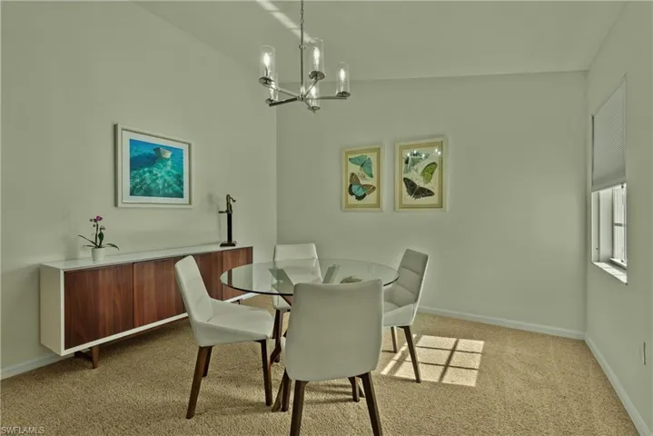 Carpeted dining area with vaulted ceiling and an inviting chandelier