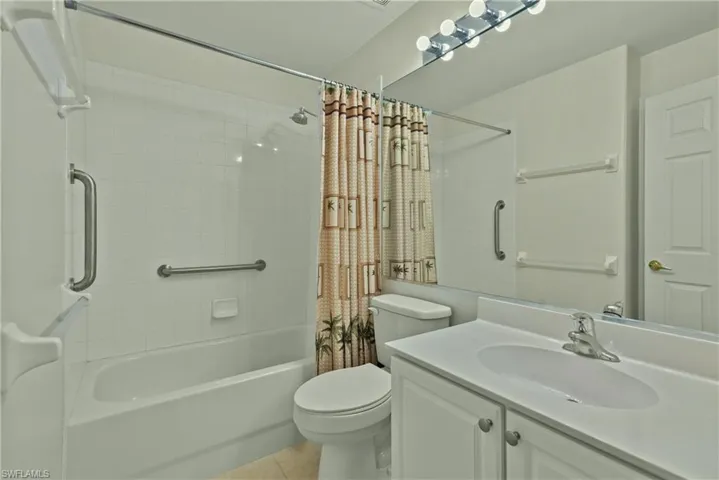 Full bathroom with tile patterned floors, vanity, shower / tub combo, and toilet