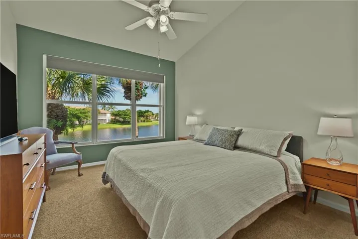 Carpeted bedroom featuring ceiling fan, lofted ceiling, and a water view