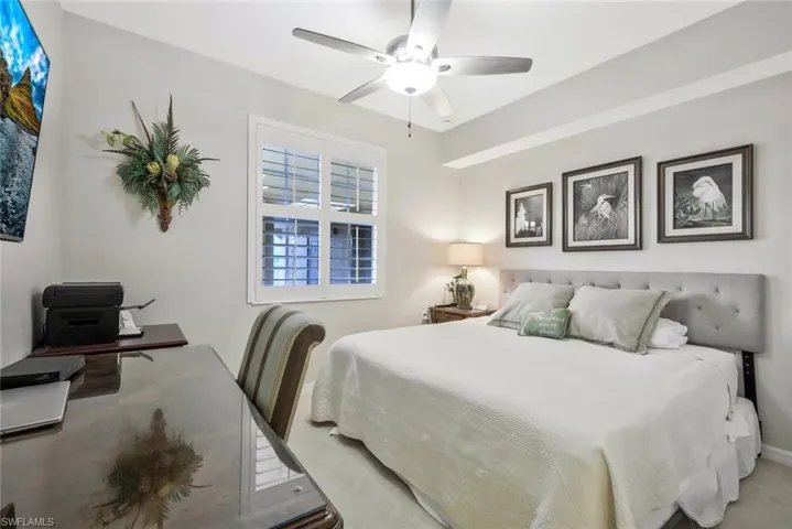 Carpeted bedroom with a ceiling fan and an office area