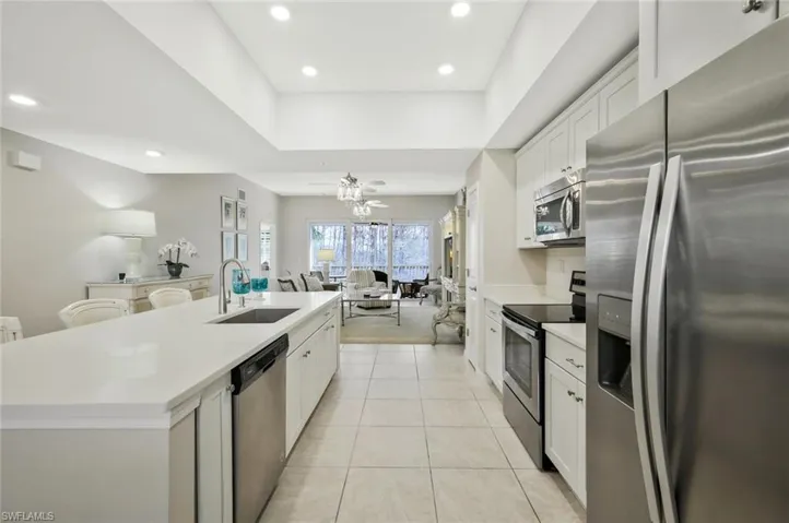 Kitchen featuring stainless steel appliances, open floor plan, a kitchen island with sink, white cabinets, and recessed lighting