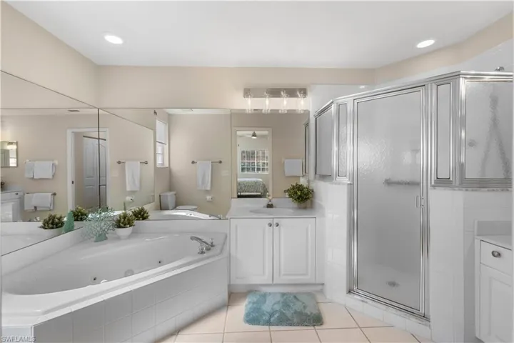 Full bathroom with a stall shower, connected bathroom, a tub with jets, tile patterned flooring, and vanity