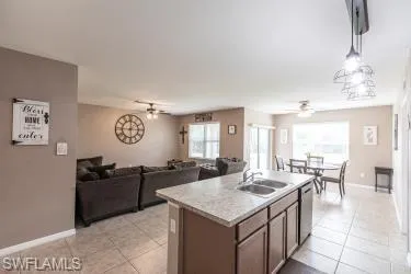 Kitchen featuring light countertops, ceiling fan, a kitchen island with sink, and open floor plan
