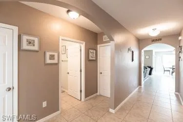 Corridor featuring arched walkways and light tile patterned floors