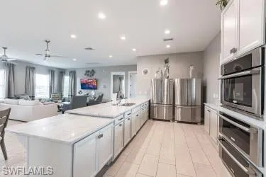 Kitchen featuring appliances with stainless steel finishes, white cabinetry, open floor plan, a warming drawer, and recessed lighting