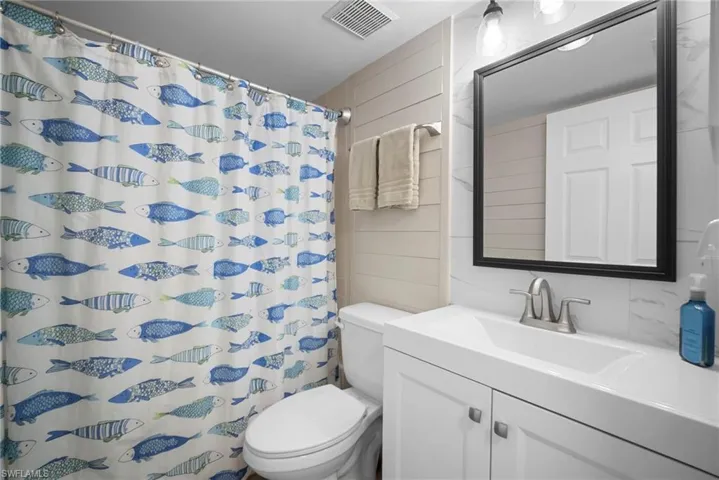 Bathroom featuring a shower with curtain, vanity, and wood walls