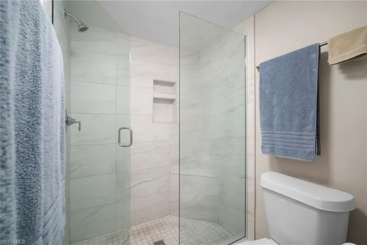 Full bath featuring a shower stall and toilet