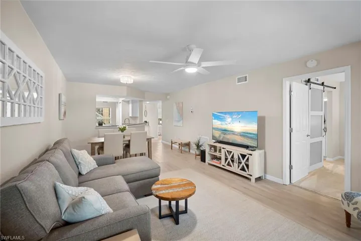 Living room with a barn door, light wood-style floors, and ceiling fan