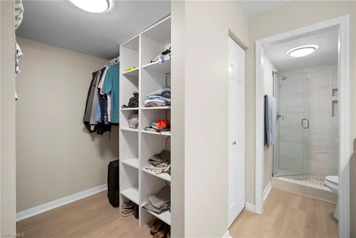 Walk in closet with light wood finished floors