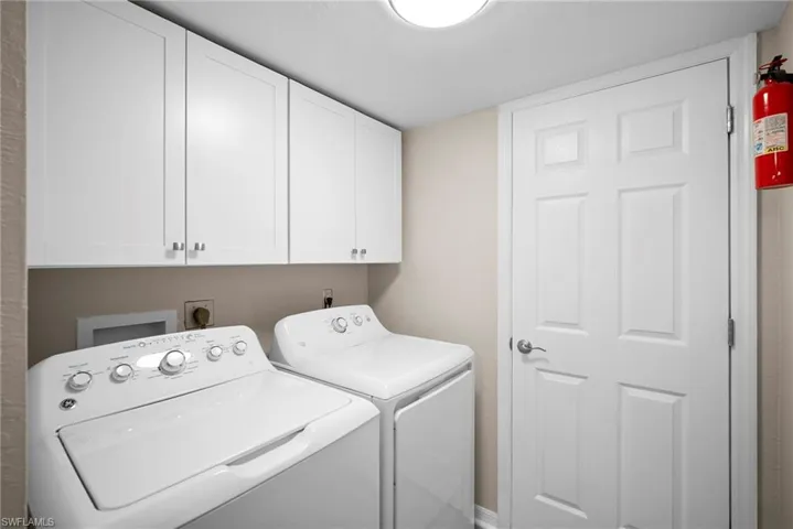 Washroom with cabinet space and washing machine and clothes dryer