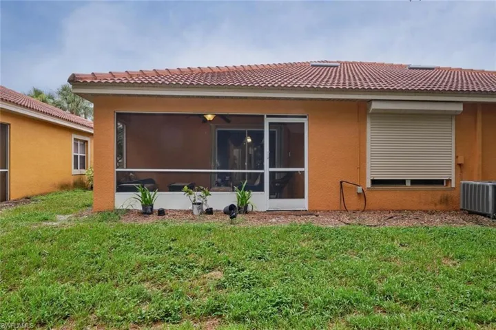 Back of property featuring central air condition unit, a sunroom, and a yard