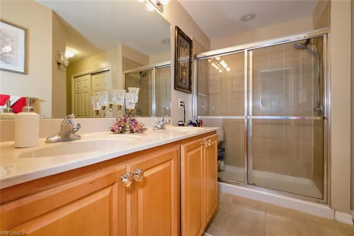 Bathroom with double vanity, tile patterned flooring, and a shower with shower door