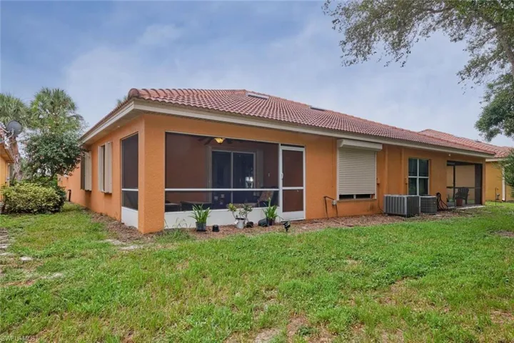 Rear view of house with a sunroom/lanai, a lawn, and central AC unit