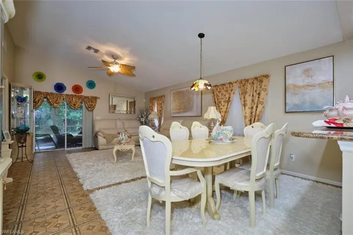 Tiled dining space with ceiling fan and vaulted ceiling