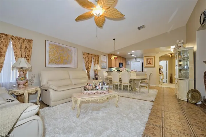 Living room with light tile patterned floors, lofted ceiling, and ceiling fan