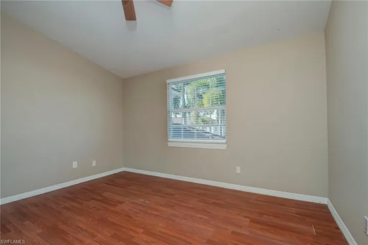 Spare room featuring dark wood-type flooring, a ceiling fan, and lofted ceiling