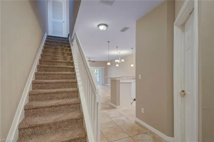 Stairs with tile patterned floors and a chandelier