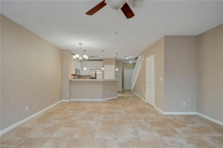 Unfurnished living room with a chandelier and a ceiling fan