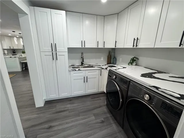 Laundry room with dark wood-style floors, washer and clothes dryer, recessed lighting, and cabinet space