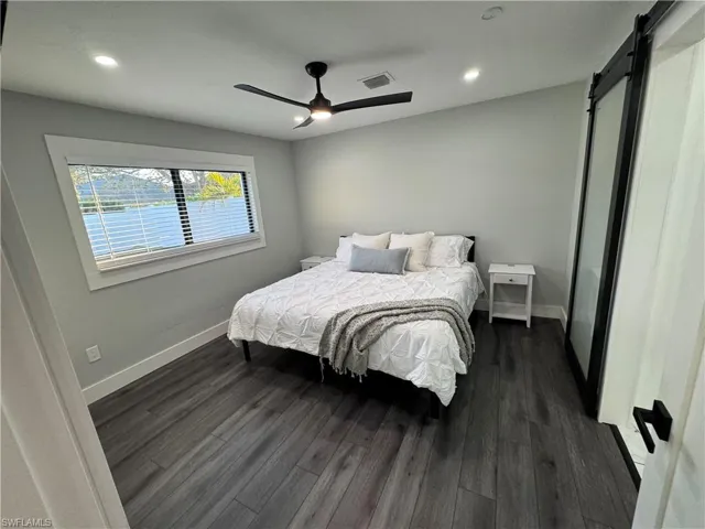 Bedroom featuring a barn door, dark wood-style floors, recessed lighting, and ceiling fan
