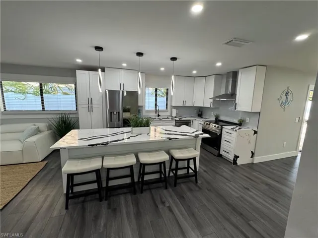 Kitchen featuring a kitchen breakfast bar, a center island, open floor plan, white cabinets, and stainless steel appliances
