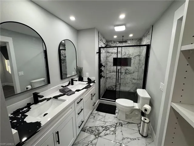 Bathroom with light marble finish floors, double vanity, a marble finish shower, and recessed lighting