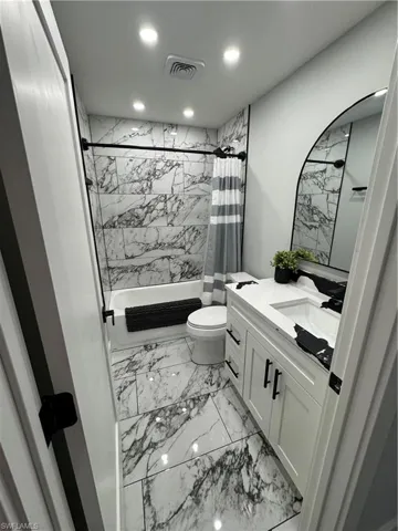 Full bathroom with vanity, light marble finish flooring, and recessed lighting